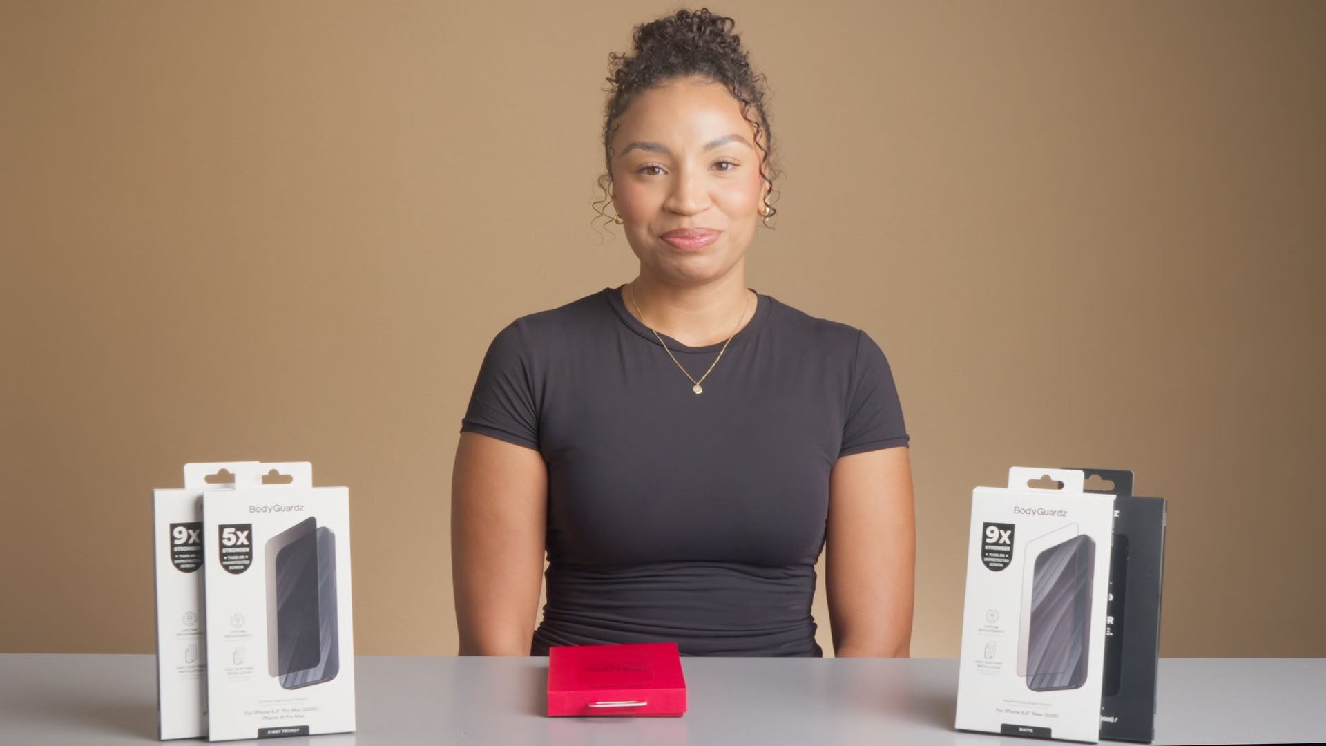 Woman sitting at a table with phone cases and screen protector packaging in front of her