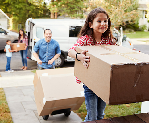 Family moving in and unpacking with girl carrying moving box