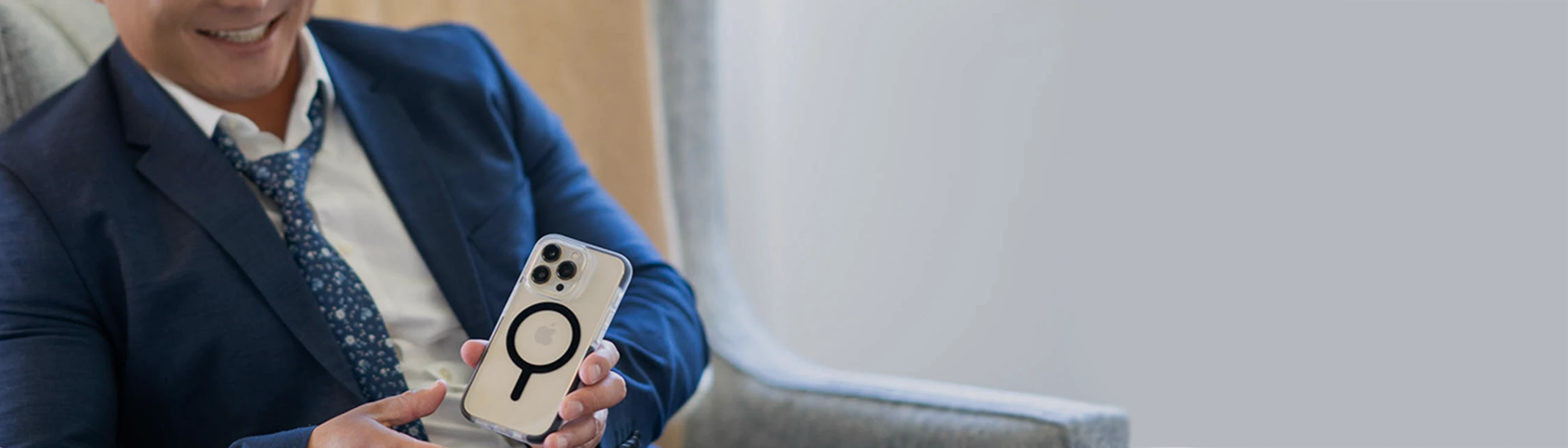 Man using an iphone on speaker phone. The phone has a green solitude phone case on it.