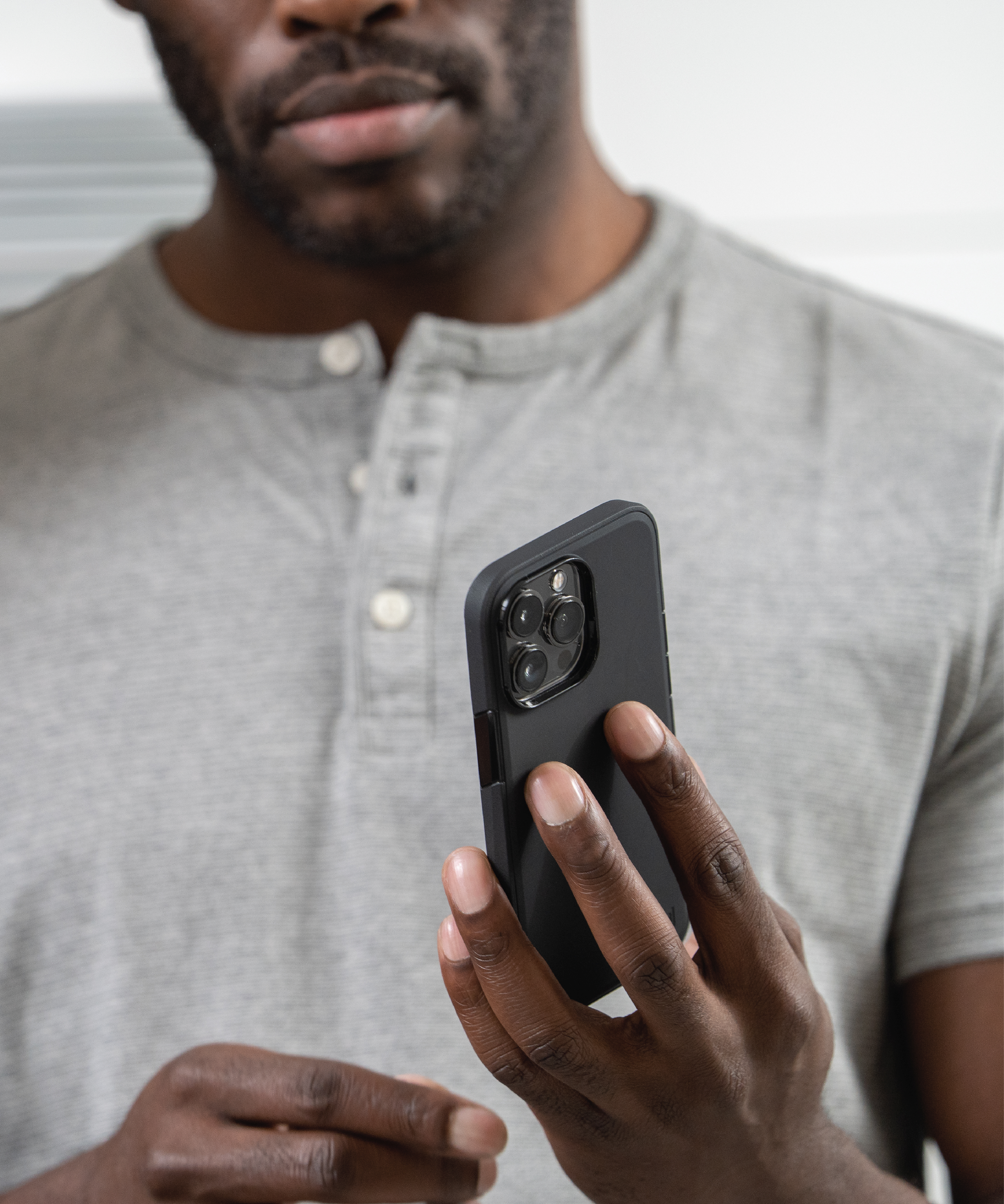 A man holding an iphone 14 with a black Solitude case on it.